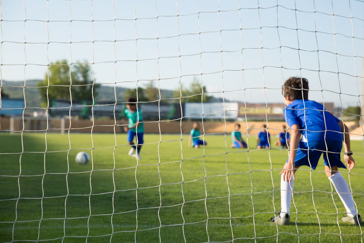 Kids enjoying a soccer match on a sunny day in Portugal with clear blue skies.
